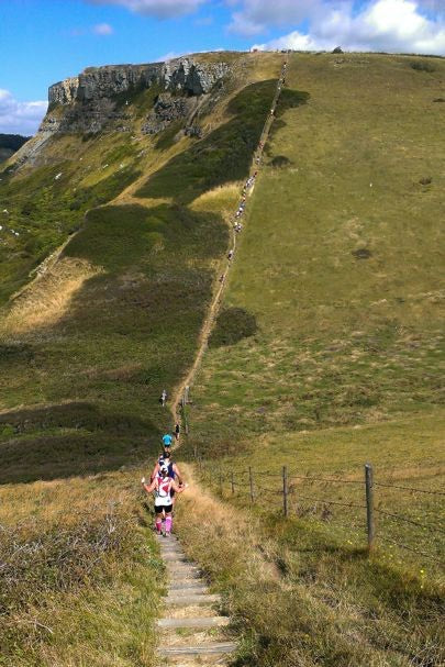 Single file of fell runners climbing a coastal hill